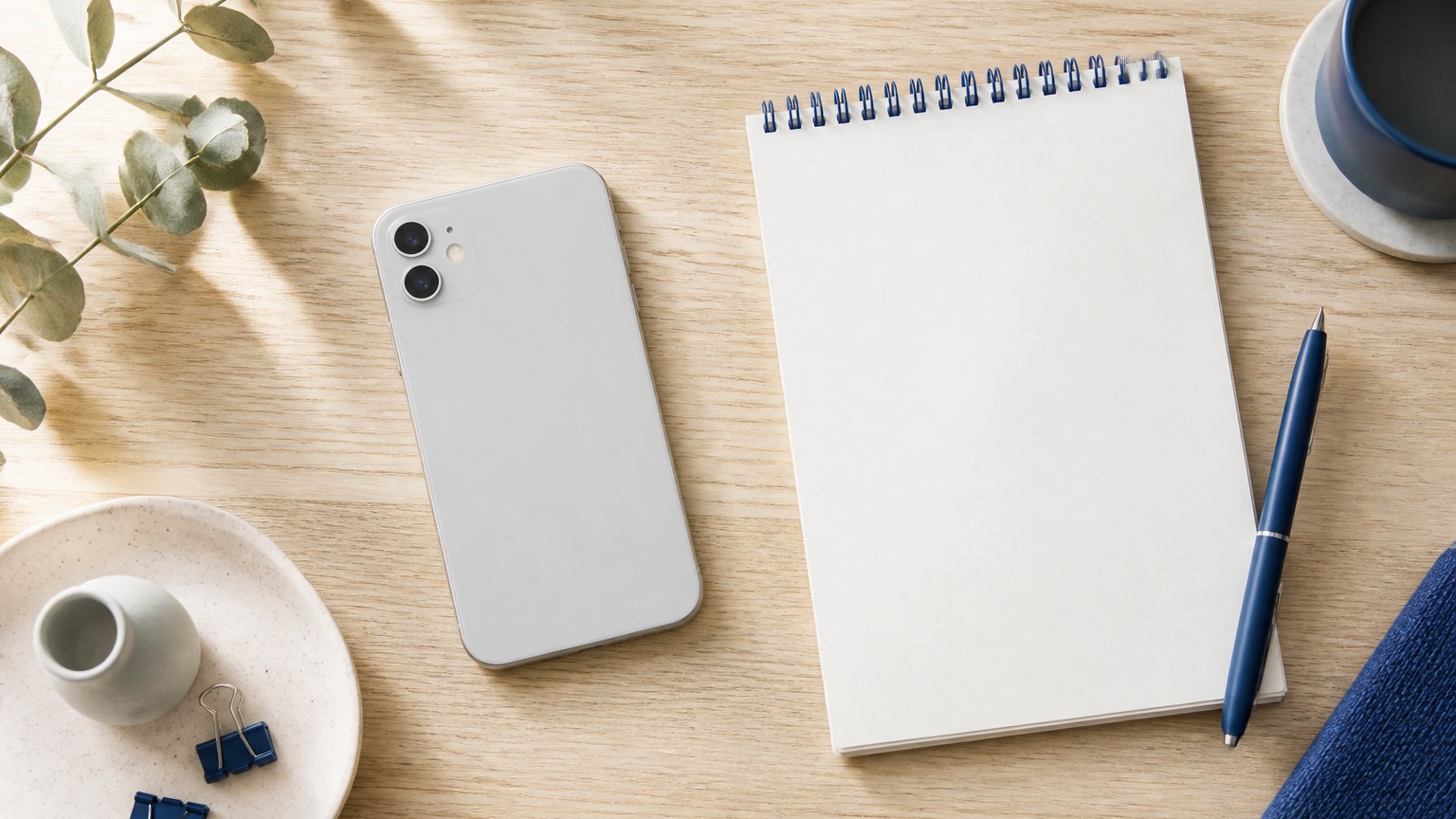 机に伏せて置いたスマートフォンとメモ帳のイメージ